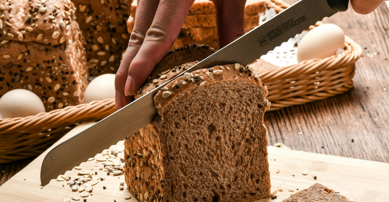 Volkorenbrood met zaden wordt aangesneden op een snijplank